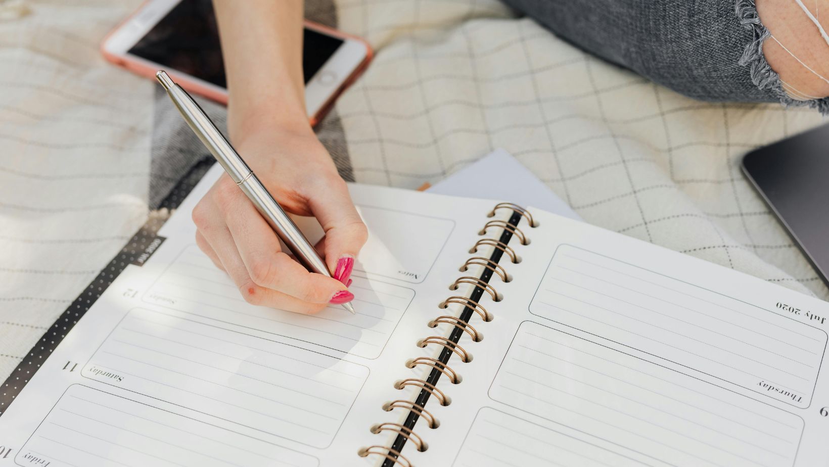 Woman taking notes in her diary while sitting in a park.